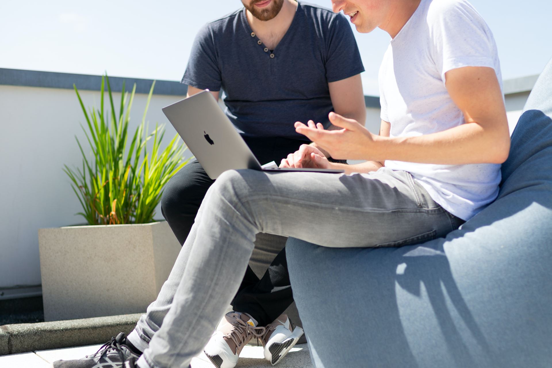 a man and a woman sat on a sofa speak with eachother, the woman has a laptop on her lap