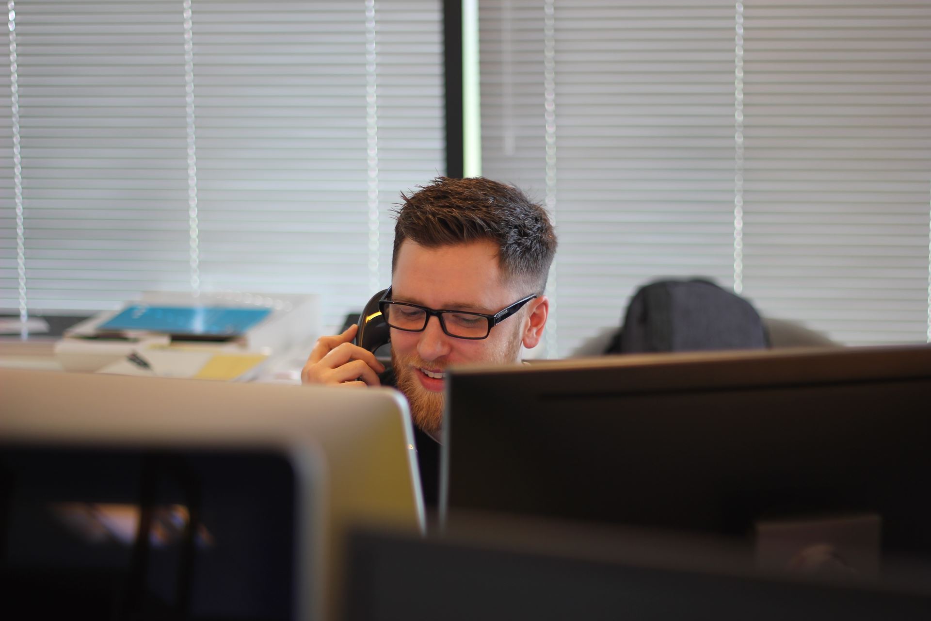 a male receptionist answering a phone sat in front of a computer